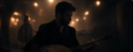 Loş ışıklı sahnede saz çalan müzisyen